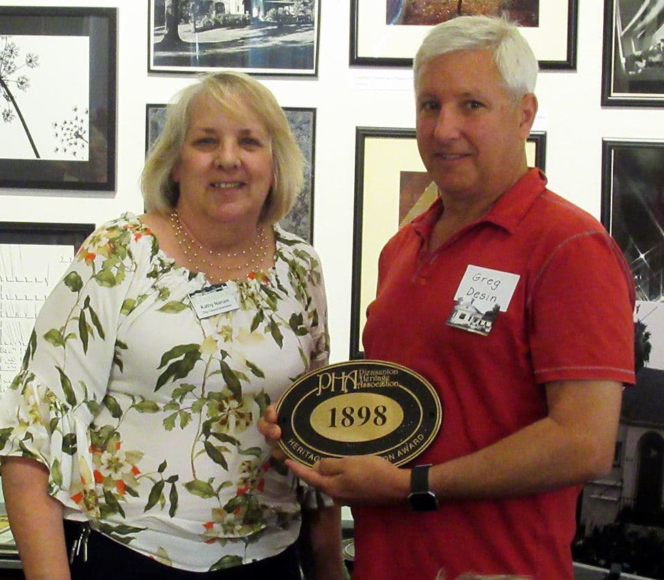 Council Member Kathy Narum presenting historic plaques to the Desin family