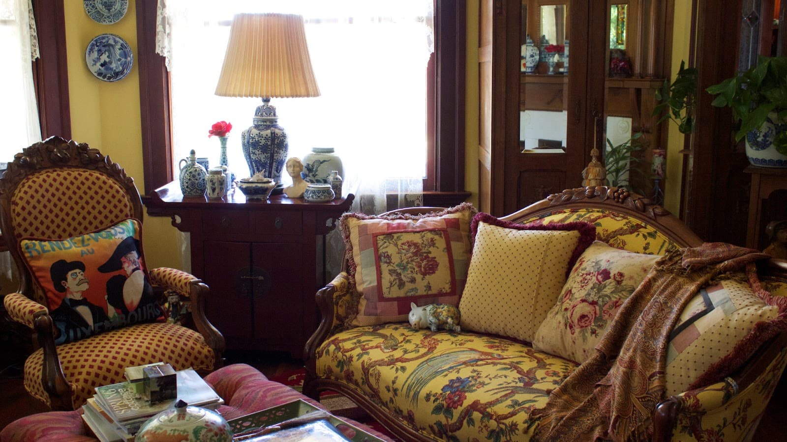 A furnished Victorian parlour with patterned wallpaper and a marble fireplace